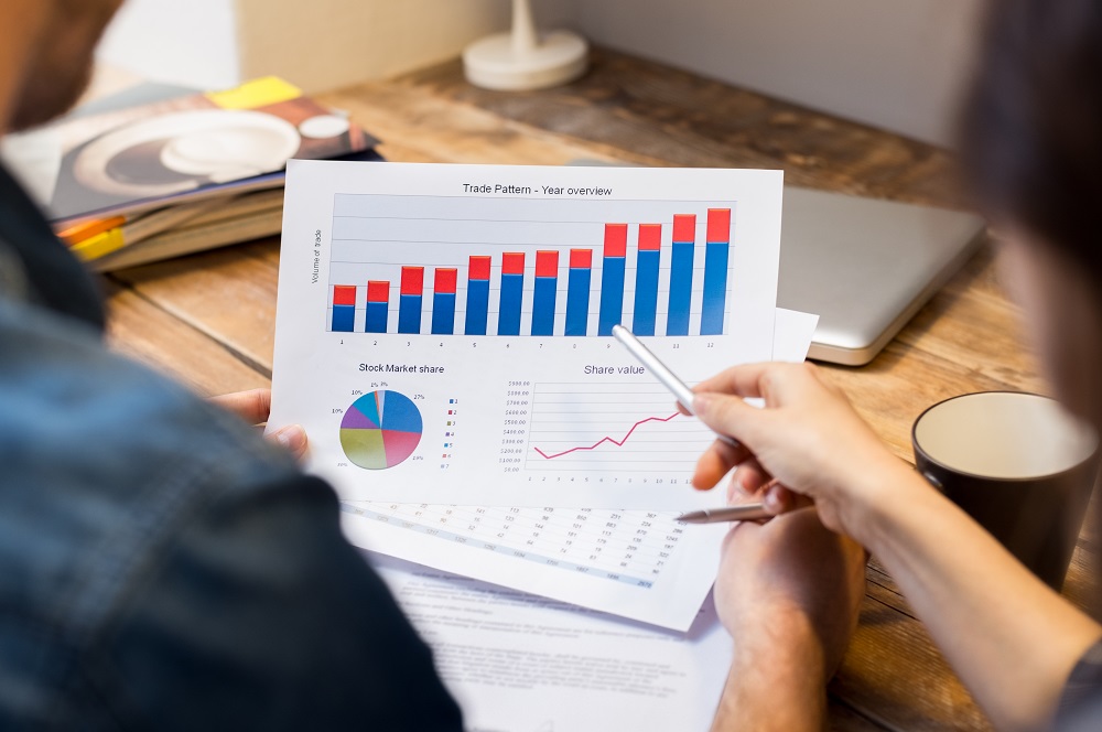 Closeup of businessman and woman discussing on stockmarket document in office